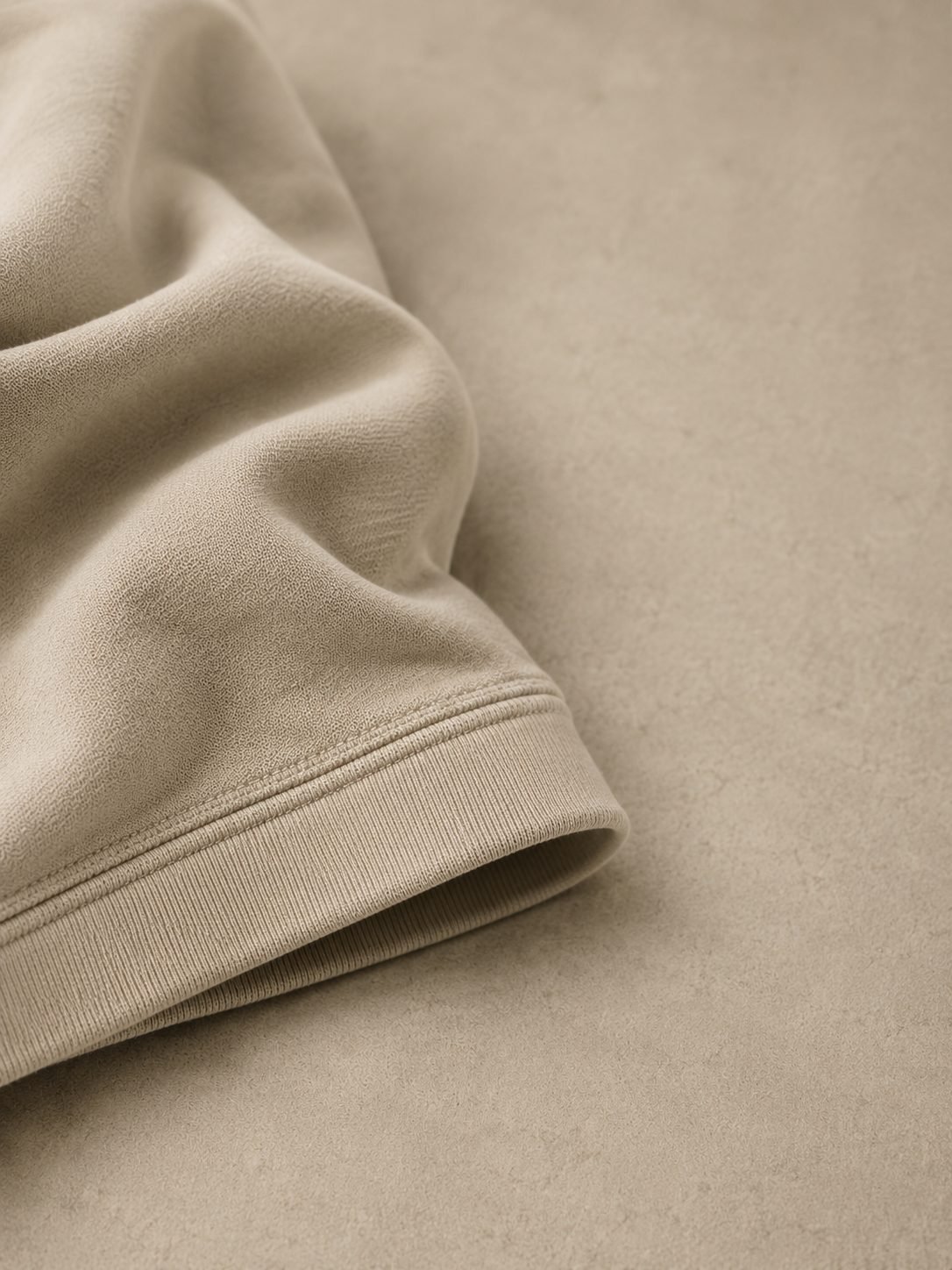 Folded heavyweight cream Ondrea t-shirt, showing the dense knit and ribbed hem.