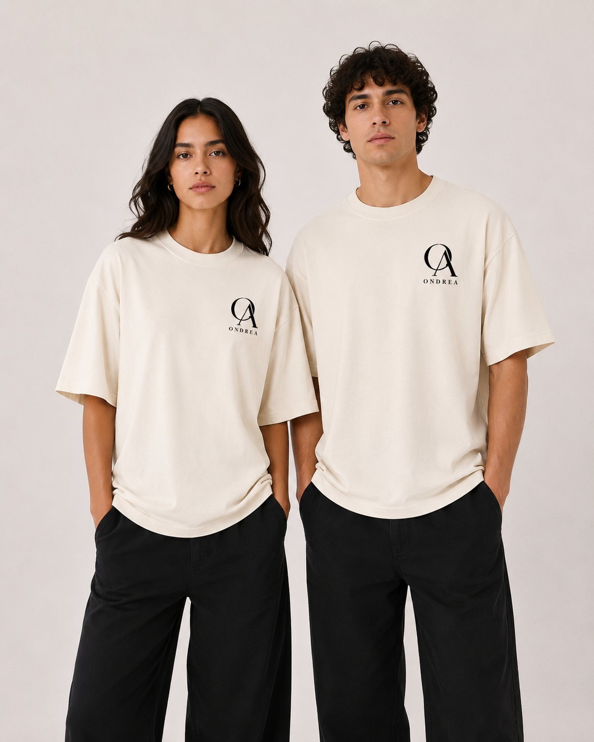 Two models wearing the ecru Ondrea oversized tee against a plaster backdrop.